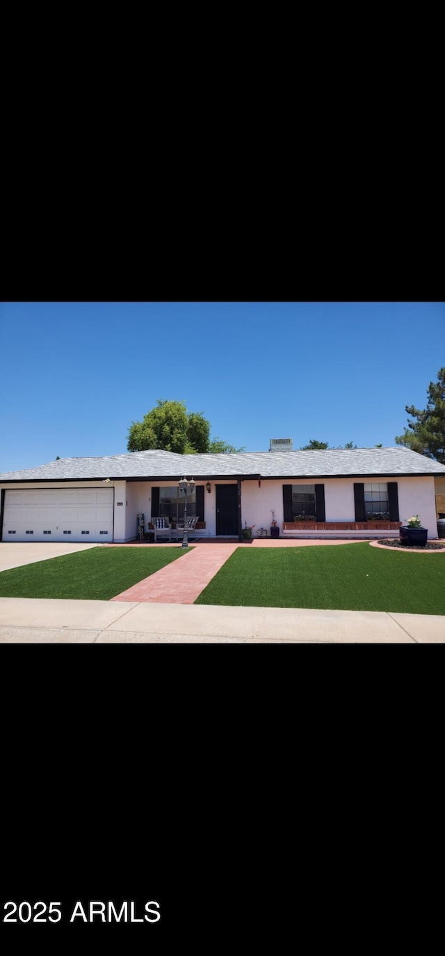 ranch-style home featuring a front yard, an attached garage, and driveway