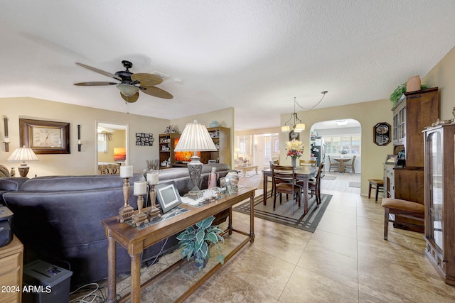 tiled living room featuring lofted ceiling, a textured ceiling, and ceiling fan