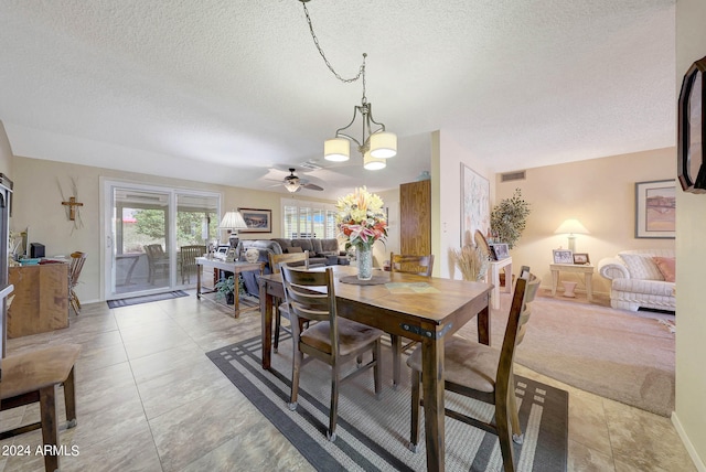 dining space featuring a textured ceiling, light tile patterned floors, and ceiling fan with notable chandelier