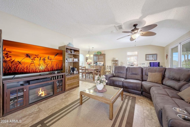 living room featuring ceiling fan, light tile patterned flooring, a textured ceiling, and lofted ceiling