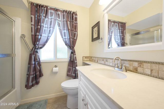 bathroom featuring vanity, toilet, decorative backsplash, and a shower with shower door