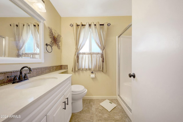 bathroom featuring a shower with door, vanity, toilet, and a healthy amount of sunlight