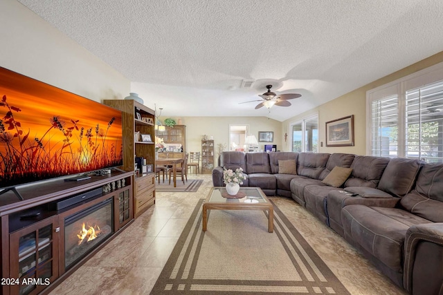 living room featuring lofted ceiling, a textured ceiling, light tile patterned flooring, and ceiling fan