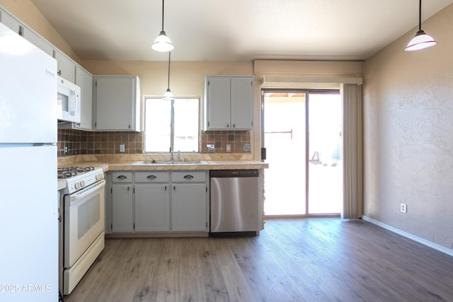 kitchen with hanging light fixtures, tasteful backsplash, sink, and white appliances