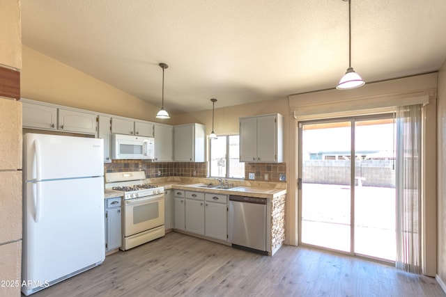 kitchen with vaulted ceiling, white appliances, sink, and hanging light fixtures