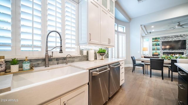 kitchen with baseboards, light wood-type flooring, white cabinetry, a sink, and dishwasher