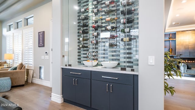 wine area with baseboards, a sink, light wood-style flooring, and visible vents