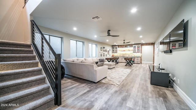 living room with light wood-style flooring, a ceiling fan, recessed lighting, visible vents, and stairway