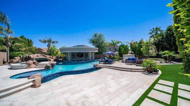 outdoor pool with an in ground hot tub, an outbuilding, a storage structure, fence, and a patio