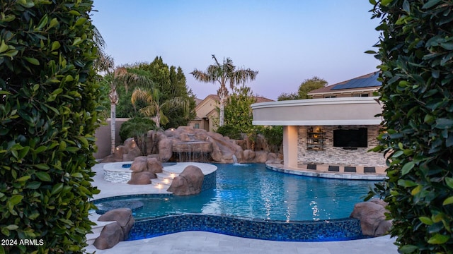 pool at dusk with a patio area and an outdoor pool