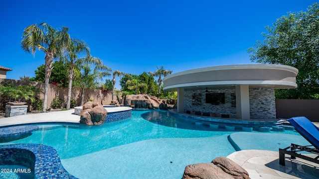 view of pool featuring fence, a water slide, and a pool with connected hot tub