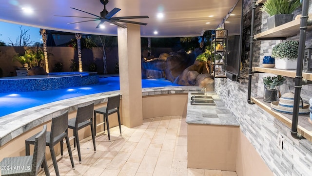 pool with exterior bar, a ceiling fan, and an in ground hot tub