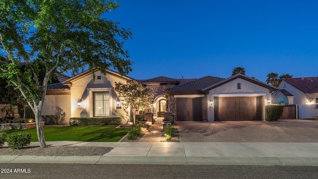 view of front of house with a tiled roof, driveway, a front yard, an attached garage, and stucco siding