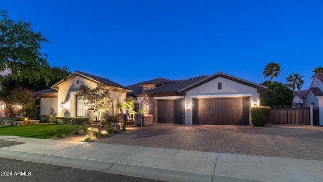 ranch-style home featuring fence, an attached garage, stucco siding, a gate, and decorative driveway