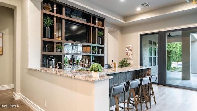 bar featuring ceiling fan, baseboards, wet bar, wood finished floors, and visible vents