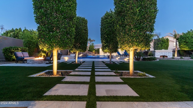 view of community featuring a lawn, a fire pit, and a patio area