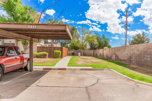 view of parking with a yard and a carport