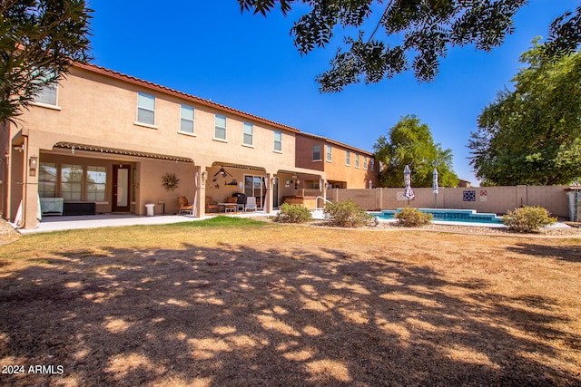 rear view of house with a fenced in pool and a patio area