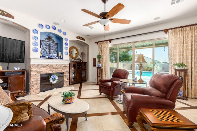 tiled living room with ceiling fan and a fireplace