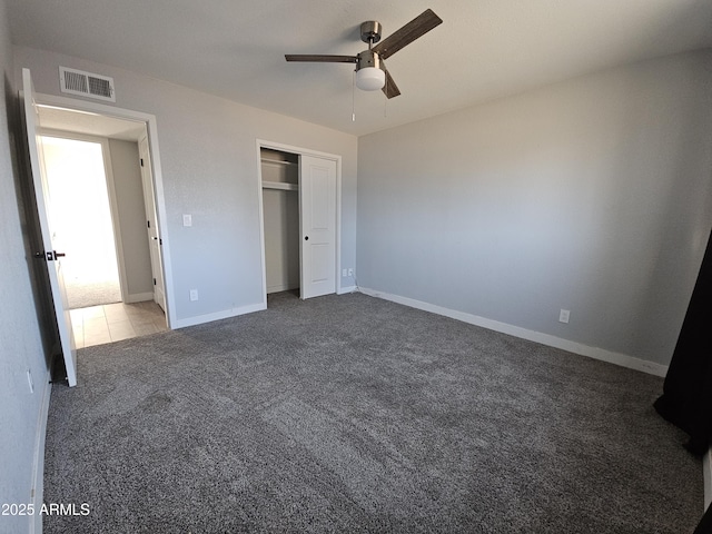 unfurnished bedroom with ceiling fan, a closet, and dark colored carpet