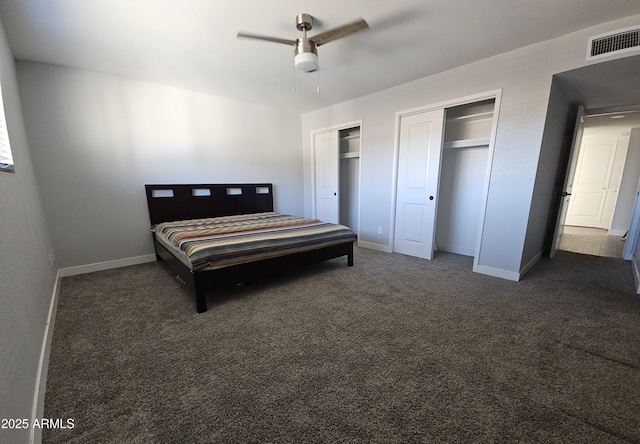 carpeted bedroom with ceiling fan and two closets