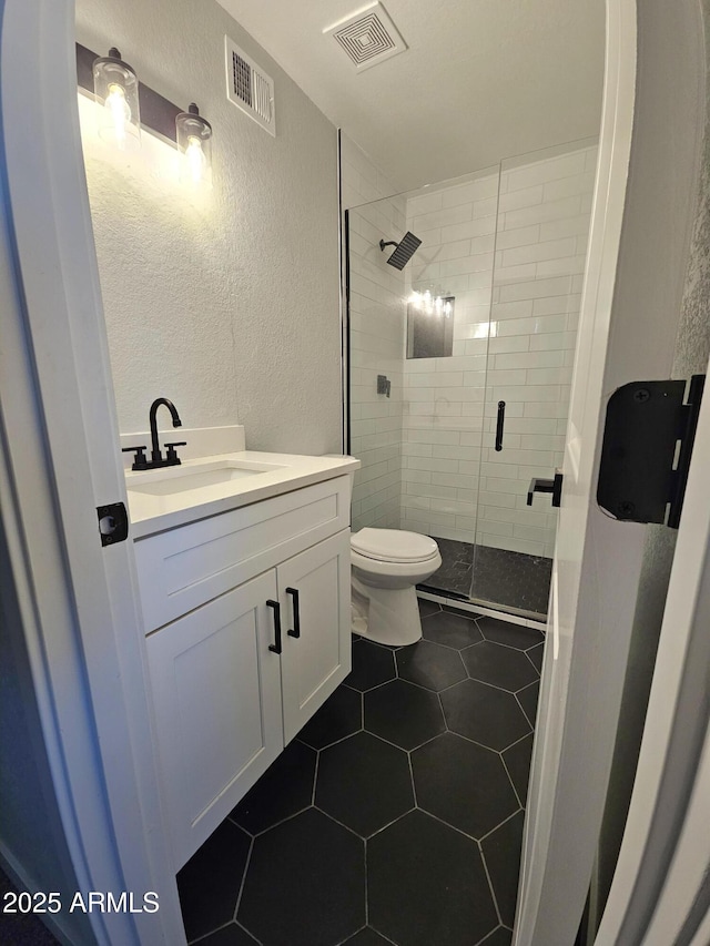 bathroom with tile patterned flooring, toilet, vanity, and walk in shower