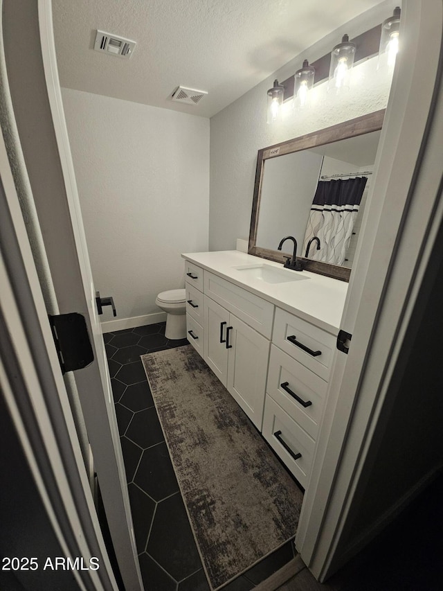 bathroom featuring toilet, tile patterned floors, a textured ceiling, vanity, and curtained shower