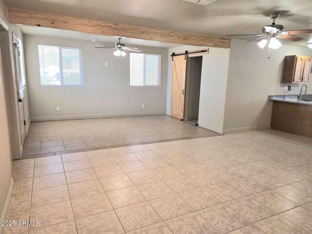 13245 N Betty Angel Way, Florence, AZ 85132 - unfurnished room with a ceiling fan, a barn door, baseboards, light tile patterned flooring, and beamed ceiling