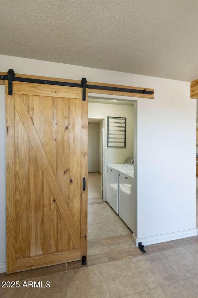 13245 N Betty Angel Way, Florence, AZ 85132 - laundry area featuring a barn door, washing machine and dryer, a textured ceiling, light tile patterned floors, and baseboards