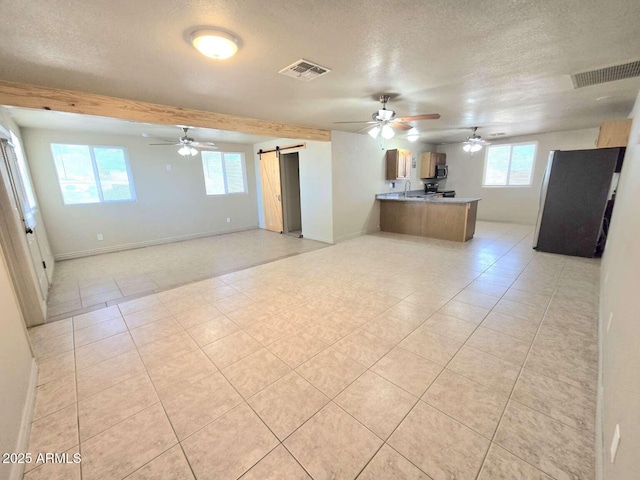13245 N Betty Angel Way, Florence, AZ 85132 - unfurnished living room with a barn door, a ceiling fan, a textured ceiling, healthy amount of natural light, and light tile patterned floors