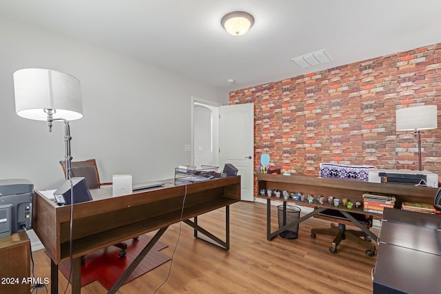 home office featuring brick wall and light hardwood / wood-style flooring