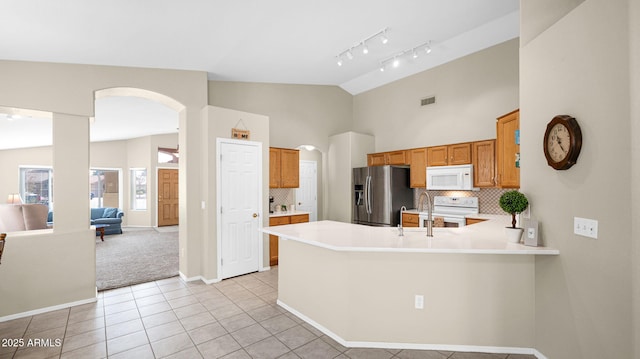 kitchen with visible vents, white appliances, arched walkways, a peninsula, and light countertops