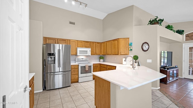 kitchen with white appliances, a peninsula, light tile patterned flooring, and light countertops