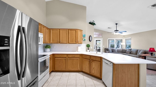 kitchen with visible vents, a peninsula, light tile patterned flooring, white appliances, and a sink