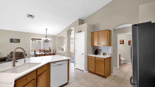 kitchen featuring visible vents, a sink, freestanding refrigerator, lofted ceiling, and dishwasher