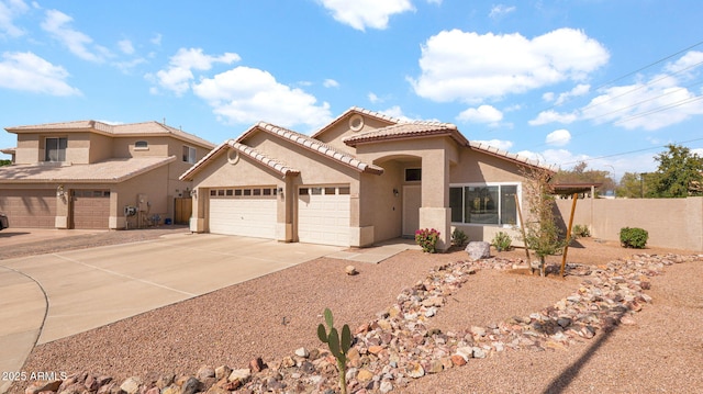 mediterranean / spanish home with fence, an attached garage, stucco siding, concrete driveway, and a tile roof