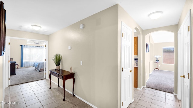 hall with arched walkways, light colored carpet, and a wealth of natural light