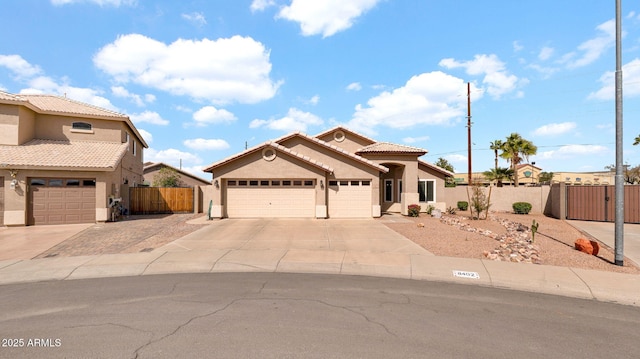 mediterranean / spanish home with fence, a tile roof, stucco siding, driveway, and a gate