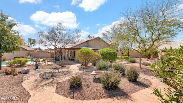 rear view of house featuring a patio, a fenced backyard, a fenced in pool, and stucco siding