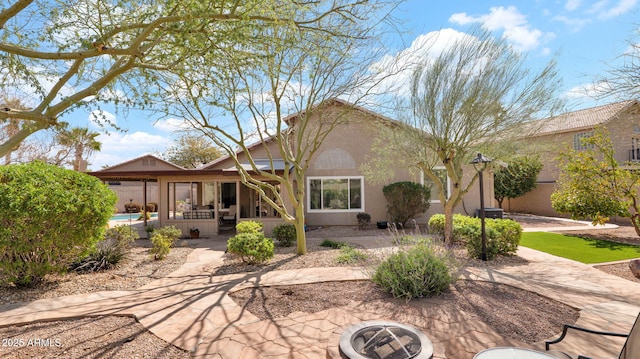 back of property with stucco siding and a patio