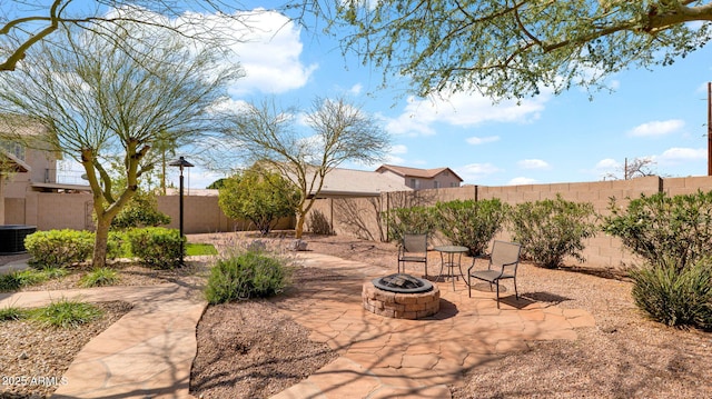 view of patio / terrace featuring central AC unit, a fenced backyard, and an outdoor fire pit