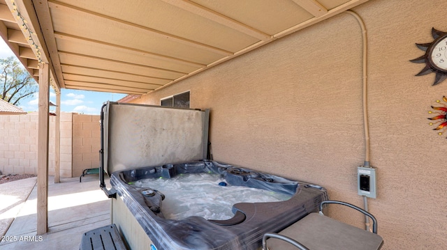 view of patio with fence and a hot tub