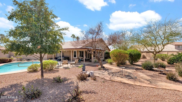 back of house featuring a patio, a fenced in pool, and stucco siding