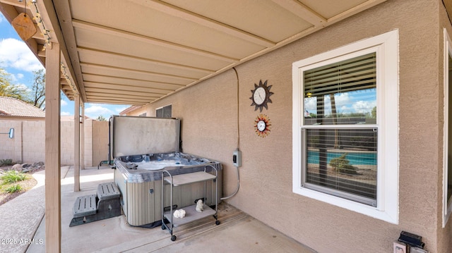 view of patio featuring fence and a hot tub