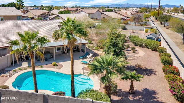 view of swimming pool featuring a fenced backyard, a mountain view, a residential view, a fenced in pool, and a patio area