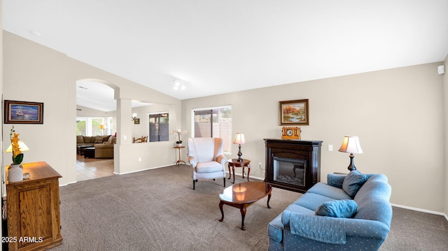 carpeted living room with arched walkways, a glass covered fireplace, tile patterned floors, and lofted ceiling