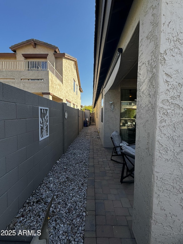 view of side of home featuring fence private yard, a patio area, and stucco siding