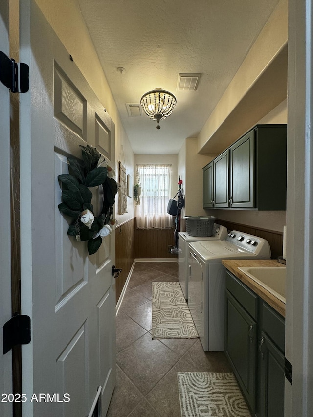 washroom with a sink, cabinet space, dark tile patterned floors, visible vents, and washer and dryer