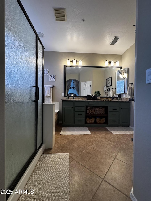 full bathroom featuring double vanity, visible vents, tile patterned flooring, and a shower stall