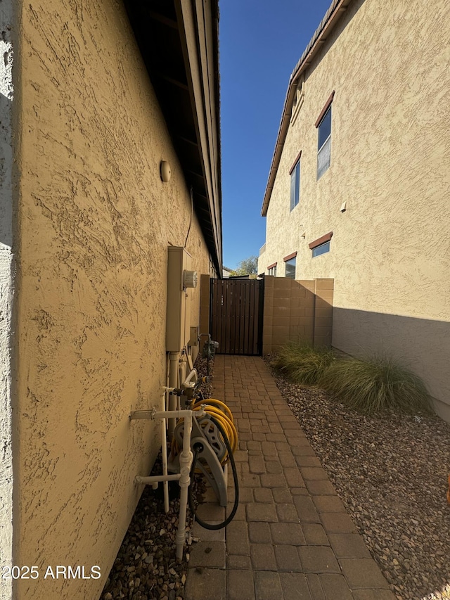 view of property exterior with a gate, fence, and stucco siding